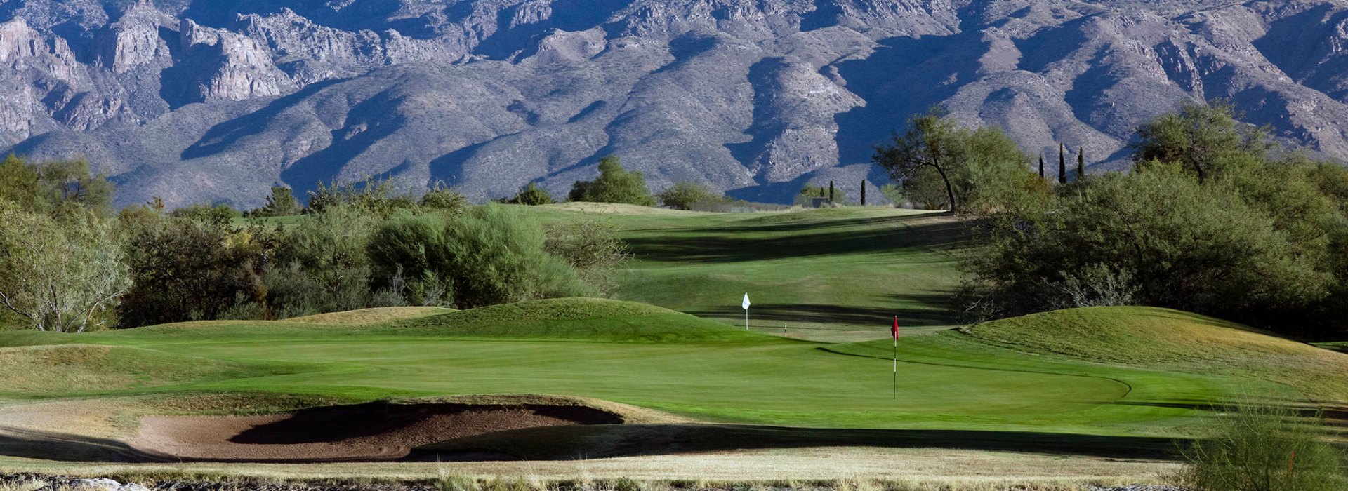 Mountains overlooking the greens at the course, red and white flags marking various points on the course.