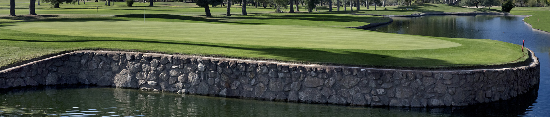 Section of the course with a vertical drop into the lake to the right, a stone wall separating land and water.